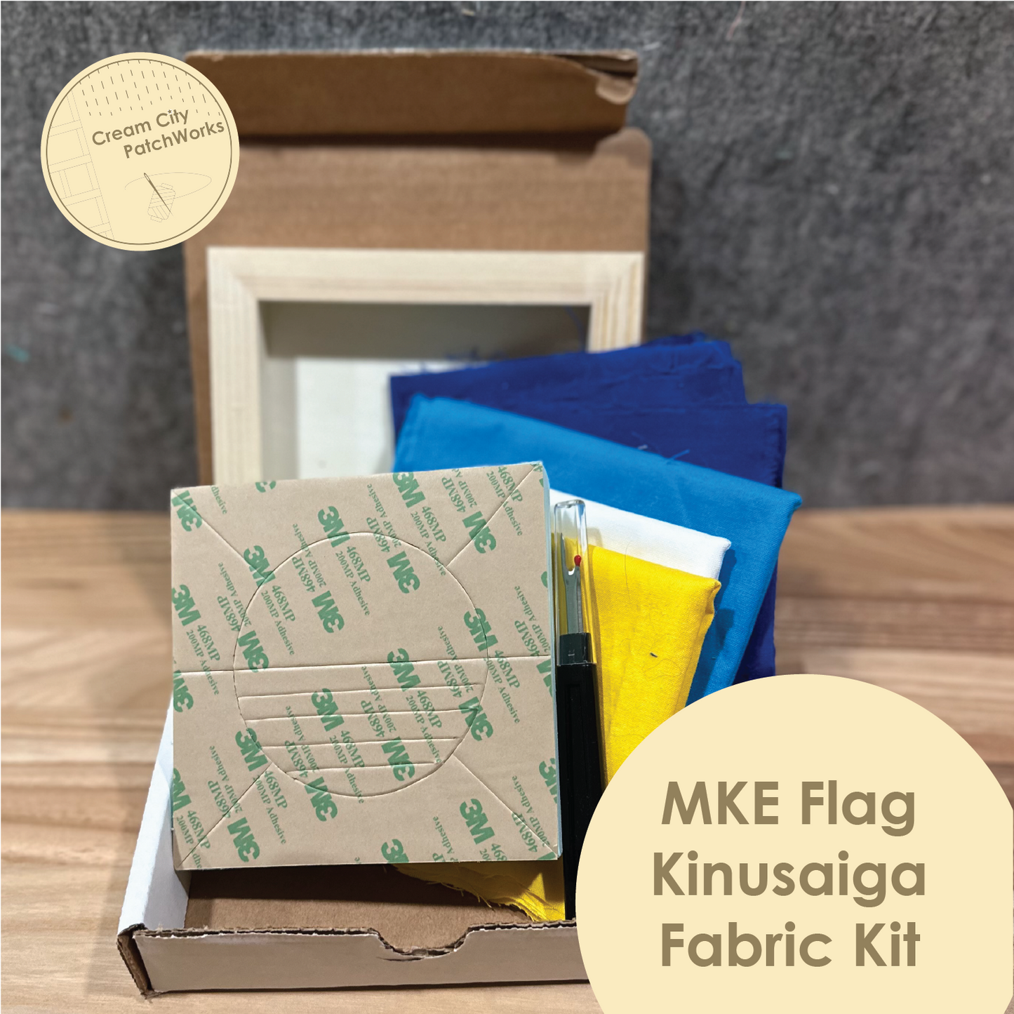 MKE Flag Kinusaiga Fabric Kit with colorful fabric samples and a cardboard box on a wooden surface.