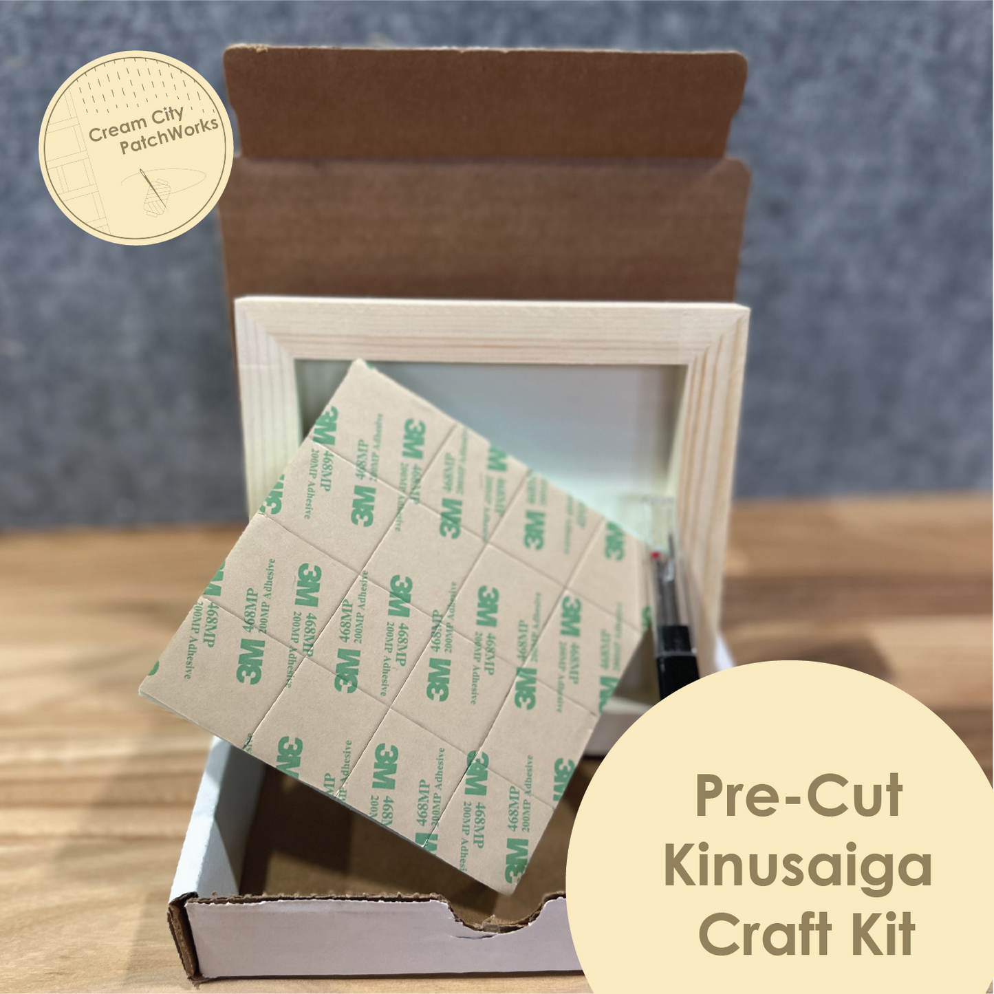 Pre-cut Kinusaiga Craft Kit with 3M tape in a cardboard box on a wooden surface.